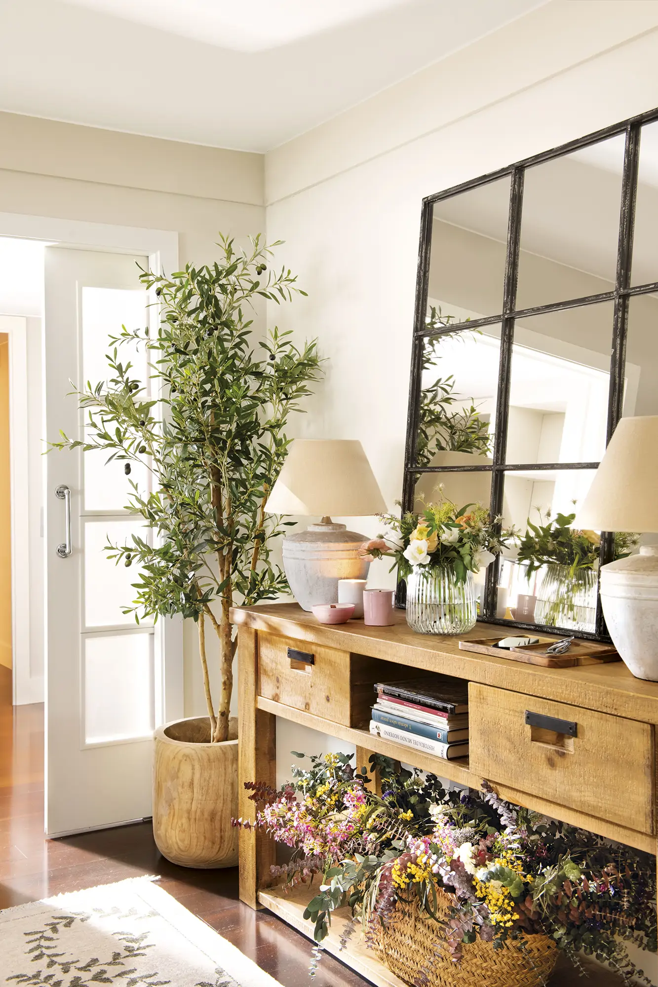 Recibidor con mueble de madera con espejo, flores secas y lámparas de mesa